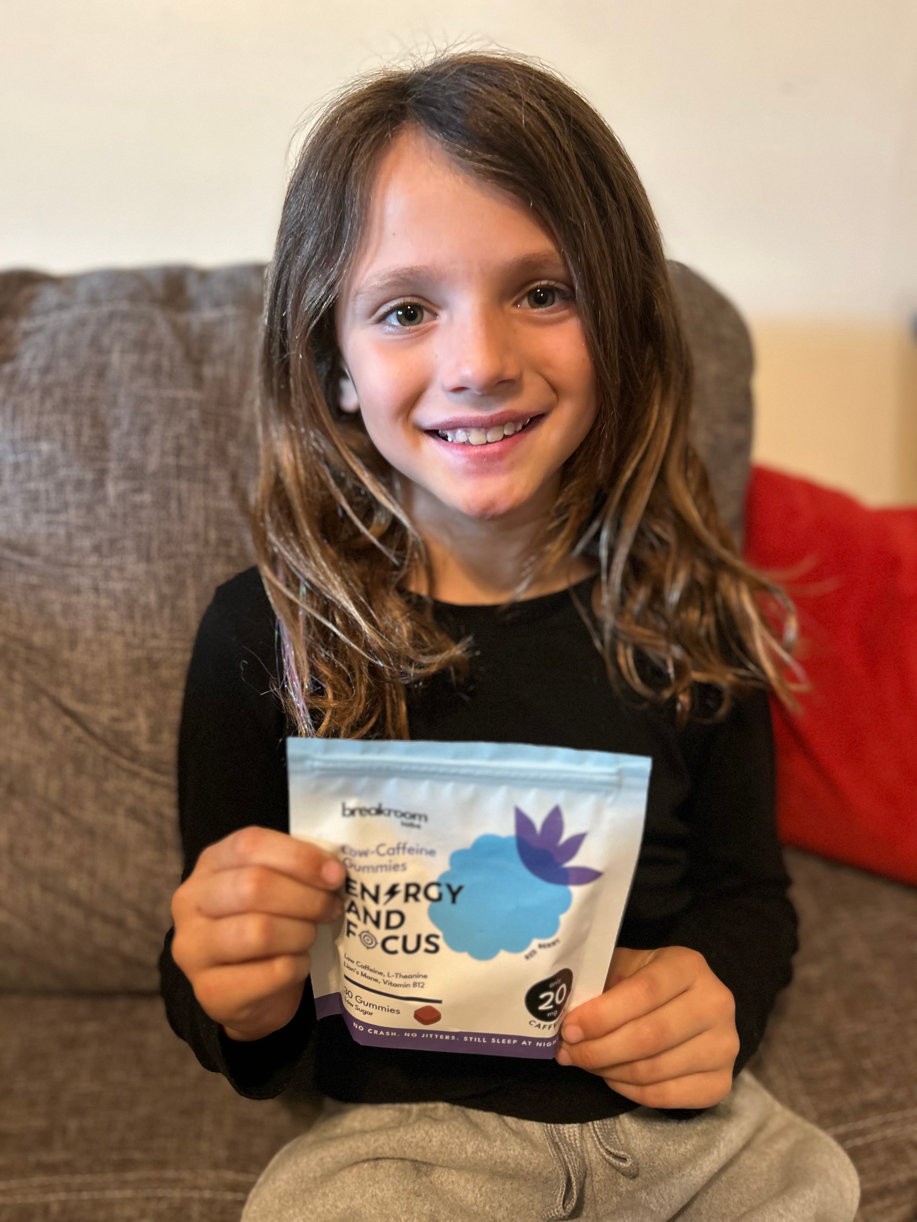 Young girl holding a package of Breakroom Labs Energy and Focus supplement.